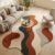 Abstract wave rug in rust orange, forest green and cream under a round wooden coffee table