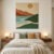 Modern abstract hand tufted wall rug with an earthy landscape design above a bed in a neutral bedroom